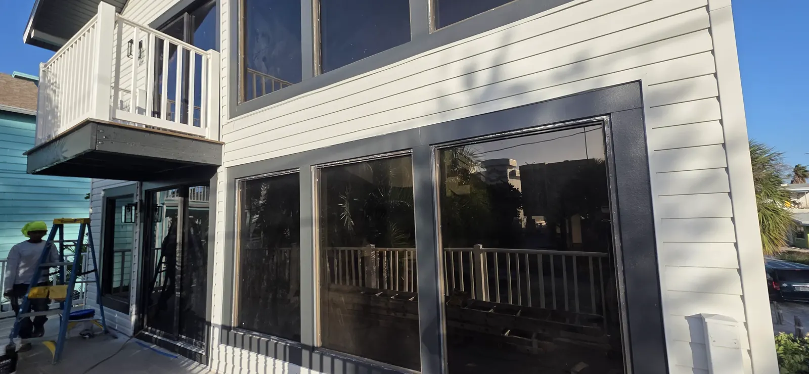 Exterior house siding and masked window surrounds with project equipment nearby