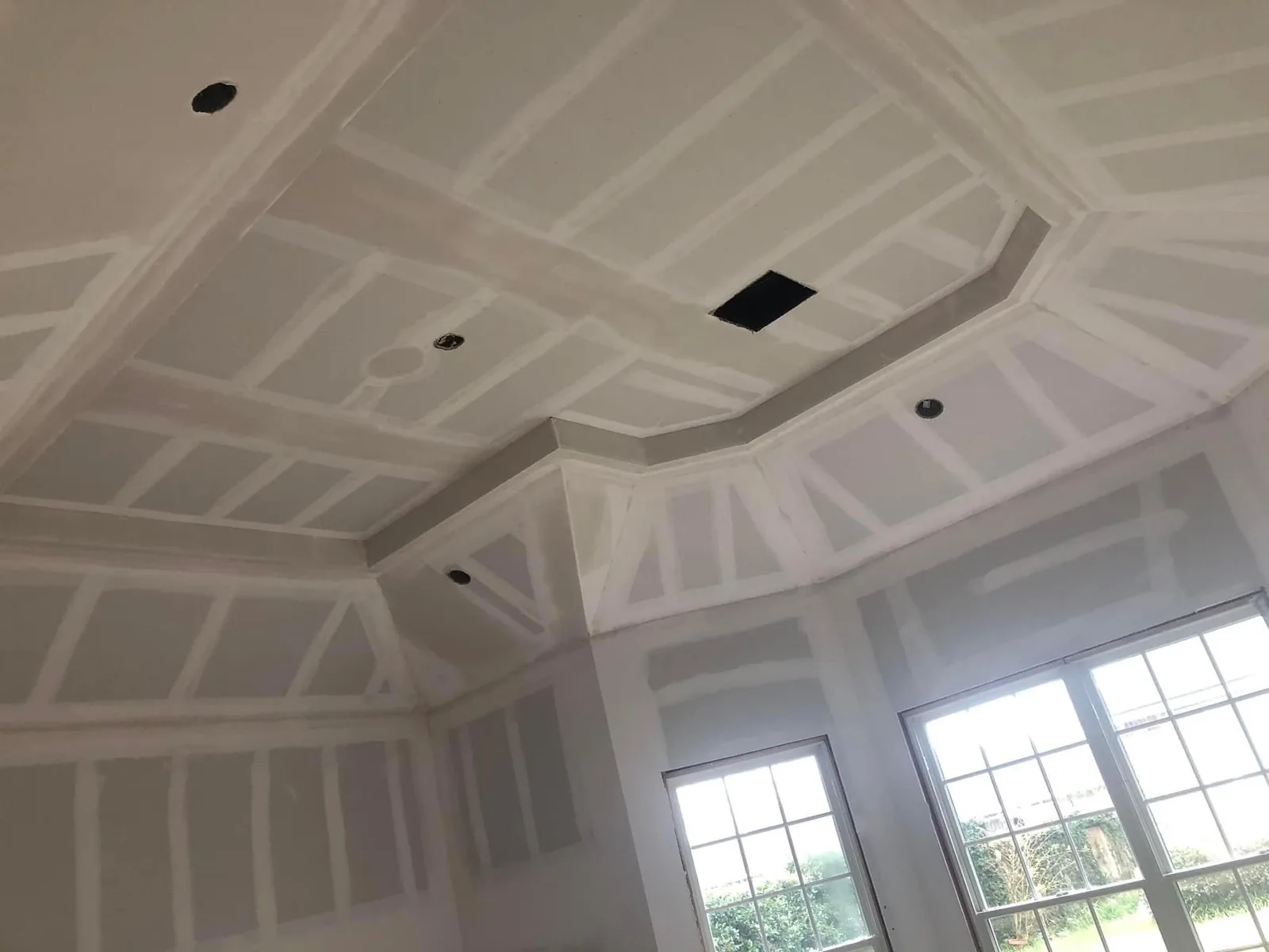 Tray ceiling detail with taped drywall seams above a bank of windows